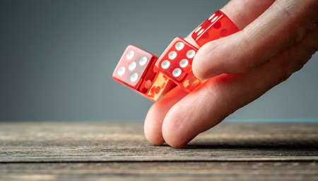 The hand is throwing red dices on the wooden table. The concept of a casino and a lucky chance to winの写真素材