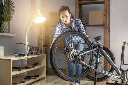 A woman is performing maintenance on his mountain bike. Concept of fixing and preparing the bicycle for the new seasonの写真素材