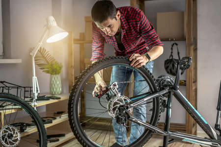 A man is disassembling a mountain bike for maintenance. Concept of fixing and preparing the bicycle for the new seasonの写真素材