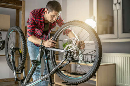 Young man fixing a mountain bike in a workshop. Concept of preparation for the new season, repair and maintenanceの写真素材
