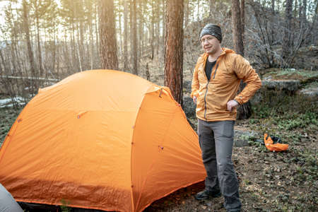 A male hiker is standing in the forest near a tent. Concept of travel, lifestyle, outdoor recreation.の写真素材
