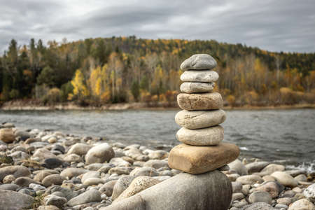 Pile of stones built in cairn on the background of river. Concept of calmness and detachment with natureの写真素材