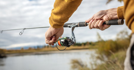 Male hands of a fisherman are holding a spinning closeup. Concept of fishing in the autumn forest, outdoor recreation, pastime, hobbyの写真素材