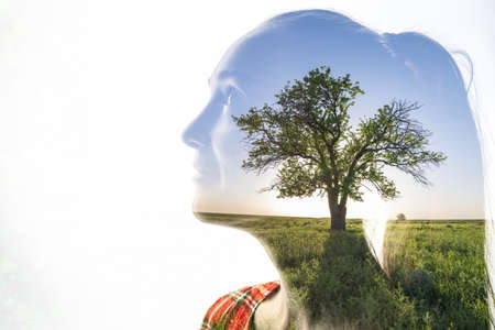 A combination of a silhouette of a woman face and a landscape with tree on a white background. Concept of the unity of nature and people, inner peace, growth, cleanliness and positive thinkingの写真素材