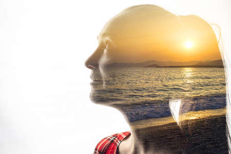 Isolated combination of the silhouette of a woman face and a seascape with a sunset. Concept of unity of nature and people, inner peace, caring for the environmentの写真素材