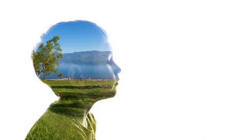 Combination of a silhouette of a face of child and a landscape with trees, grass, sky and water. Concept of the connection between man and nature, taking care of the environmentの写真素材