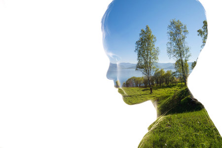 Combination of a silhouette of a face of child and a landscape with trees, grass, sky and water. Concept of the connection between man and nature, taking care of the environmentの写真素材