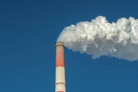 Powerful industrial factory chimney is smoking and emitting carbon dioxide into the environment. Concept of air pollution and the problem of global warmingの写真素材