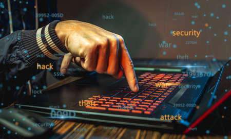 Hands in type on a laptop keyboard in close-up. The concept of cybercrime fraud and identity theft.の写真素材