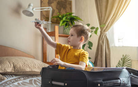 A child boy in a yellow T-shirt is playing with a toy airplane. The concept of going on a journey towards adventure.の写真素材