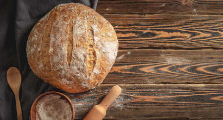 Homemade natural fresh bread with a Golden crust on a napkin on an old wooden background . The concept of baking bakery products. rustic style.の写真素材