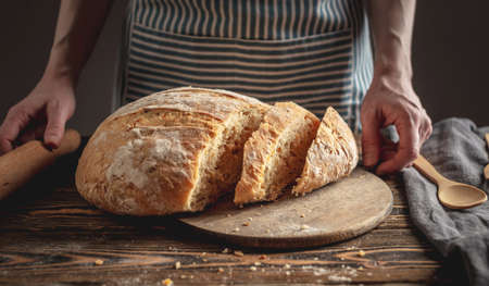 Homemade natural fresh bread with a Golden crust on a napkin on an old wooden background . The concept of baking bakery products. rustic style.の写真素材
