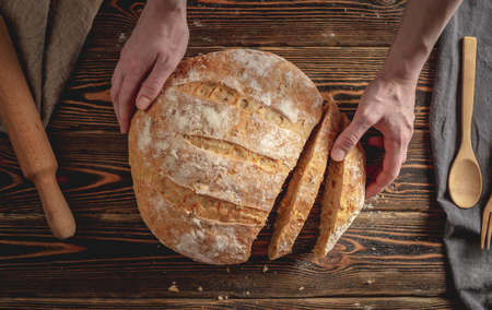 Homemade natural fresh bread with a Golden crust on a napkin on an old wooden background . The concept of baking bakery products. rustic style.の写真素材