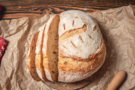 Homemade natural fresh bread with a Golden crust on a napkin on an old wooden background . The concept of baking bakery products. rustic style.の写真素材