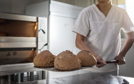 The baker is a man in the process of baking bread. Production of bakery products as a small...