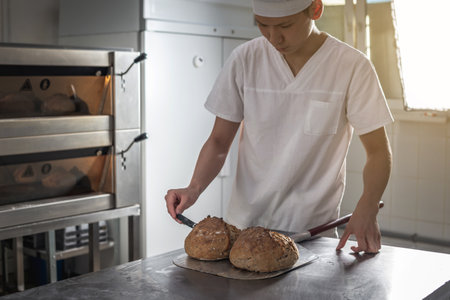 The baker is a man in the process of baking bread. Production of bakery products as a small business.の写真素材