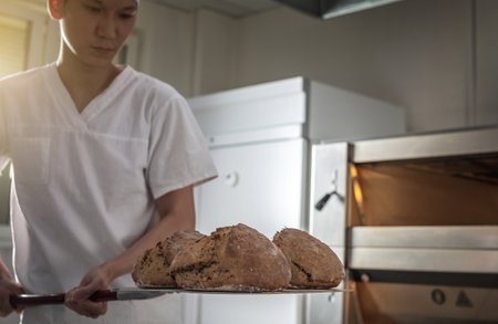 The baker is a man in the process of baking bread. Production of bakery products as a small business.の写真素材