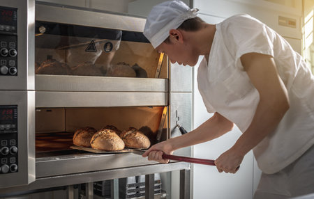 The baker is a man in the process of baking bread. Production of bakery products as a small business.の写真素材