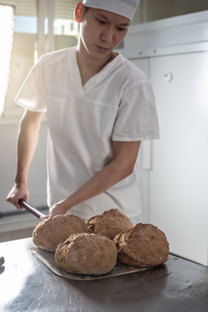 The baker is a man in the process of baking bread. Production of bakery products as a small business.の写真素材