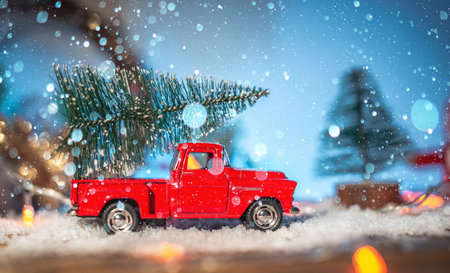 A toy red retro car carries a Christmas tree on Christmas and New Year's Eve on a blue background.の写真素材