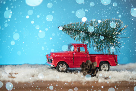 A toy red retro car carries a Christmas tree on Christmas and New Year's Eve on a blue background.の写真素材