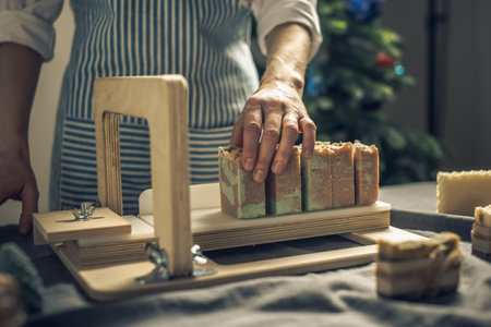 Women's hands cut homemade natural soap on a professional wood cutter. A means of eco-friendly hygiene and pleasant giftsの写真素材
