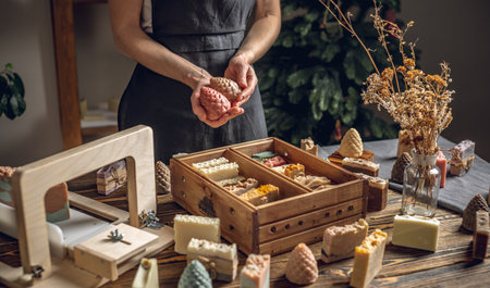 A woman soap maker holds soap in her hands in the form of colorful coniferous cones. An interesting gift for New Year's holidays and Christmas. Eco-friendly natural handmade cosmetics.の写真素材