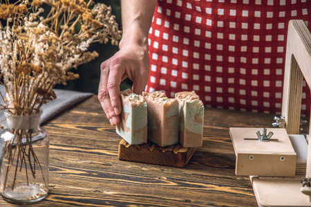 Women's hands cut homemade natural soap on a professional wood cutter. A means of eco-friendly hygiene and pleasant giftsの写真素材