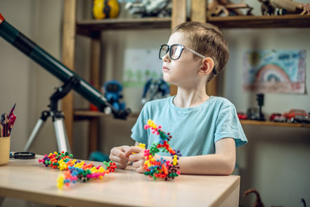 A child boy in the children's room is playing with a toy constructor for teaching the science of chemistry. Assembling molecules from elements. Children's scientific education.の写真素材