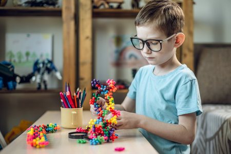 A child boy in the children's room is playing with a toy constructor for teaching the science of chemistry. Assembling molecules from elements. Children's scientific education.の写真素材