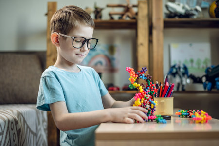 A child boy in the children's room is playing with a toy constructor for teaching the science of chemistry. Assembling molecules from elements. Children's scientific education.の写真素材