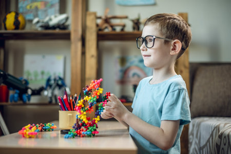 A child boy in the children's room is playing with a toy constructor for teaching the science of chemistry. Assembling molecules from elements. Children's scientific education.の写真素材