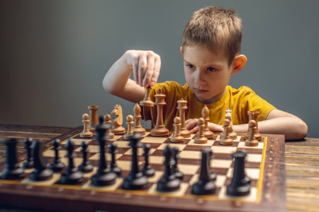 The child is a boy playing chess alone at the board. The process of thinking about a move to checkmate.の写真素材