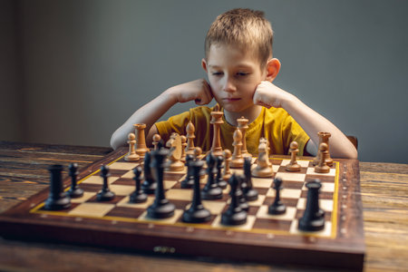 The child is a boy playing chess alone at the board. The process of thinking about a move to checkmate.の写真素材
