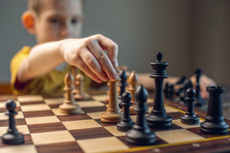 The child is a boy playing chess alone at the board. The process of thinking about a move to...