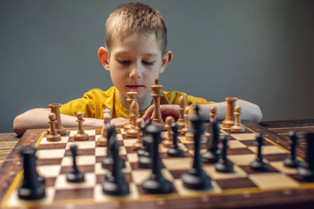 The child is a boy playing chess alone at the board. The process of thinking about a move to checkmate.の写真素材