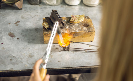 Heating with a flame jet of a metal billet of a silver ring. The work of a jeweler in the workshop