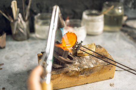 Heating with a flame jet of a metal billet of a silver ring. The work of a jeweler in the workshop