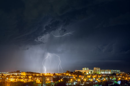 Lightning strikes in the night city among the menacing black clouds. Storm and thunderstorm.