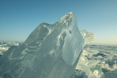 A large transparent block of ice in the rays of the sun at sunset. Beautiful winter natural abstraction of Baikal iceの写真素材