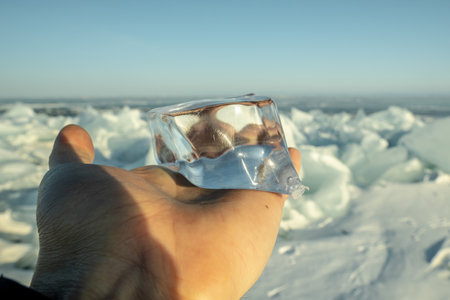 Transparent piece of ice on your hand in the rays of the setting sun. Winter natural abstraction of Baikal iceの写真素材