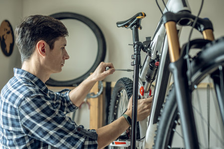 A male bicycle mechanic in the workshop disassembles a mountain bike and repairs it. Maintenance concept, preparation for the new season.の写真素材