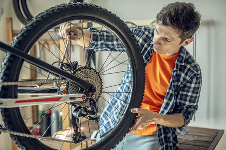 A male bicycle mechanic in the repair shop disassembles a mountain bike and repairs it. Maintenance concept, preparation for the new season.の写真素材