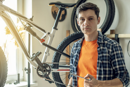 A male bicycle mechanic in the repair shop disassembles a mountain bike and repairs it. Maintenance concept, preparation for the new season.の写真素材