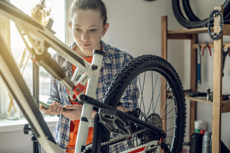 Young woman fixing a mountain bike in a repair shop. Concept of preparation for the new season, repair and maintenanceの写真素材