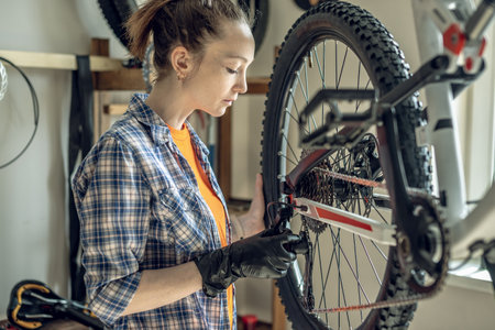 Young woman fixing a mountain bike in a repair shop. Concept of preparation for the new season, repair and maintenanceの写真素材