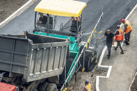 Workers lay a new asphalt coating using hot bitumen. Work of heavy machinery and paver. The view from the topの写真素材