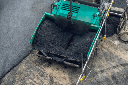Workers lay a new asphalt coating using hot bitumen. Work of heavy machinery and paver. The view from the topの写真素材