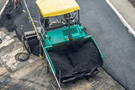 Workers lay a new asphalt coating using hot bitumen. Work of heavy machinery and paver. The view from the topの写真素材