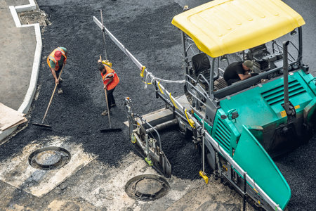 Workers lay a new asphalt coating using hot bitumen. Work of heavy machinery and paver. The view from the topの写真素材